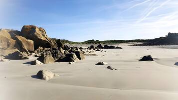 Ein Strand mit großen Felsen und blauem Himmel.