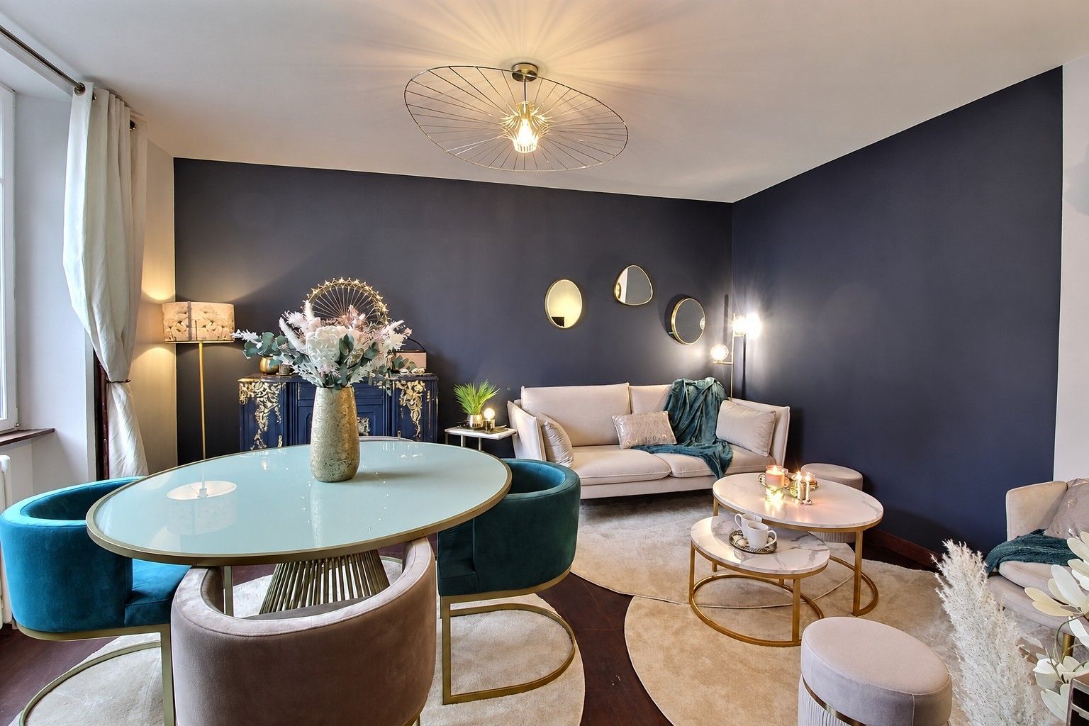 A modern living room with a round glass table, a sofa, and a coffee table. There is a decorative vase with flowers on the table.