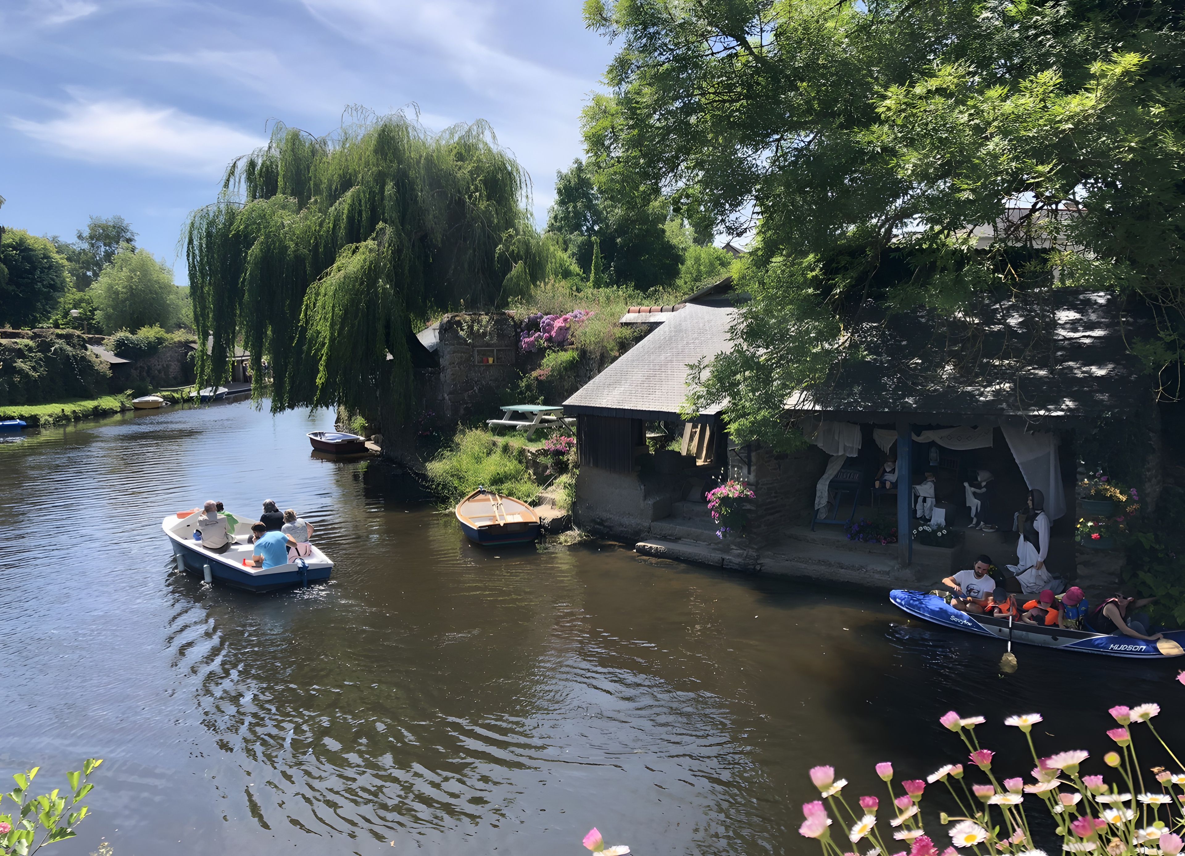 A river with boats, a small dock, and a building with a garden.