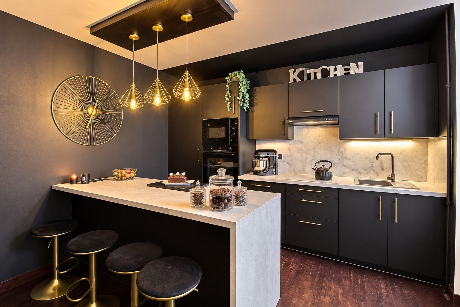 A modern kitchen with a central island, bar stools, pendant lighting, and a 'KITCHEN' sign.