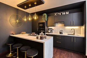 A modern kitchen with a central island, bar stools, pendant lighting, and a 'KITCHEN' sign. - Gîte "Chez nous" – Terre et Mer Cottages – Pets Welcome (Pontrieux)
