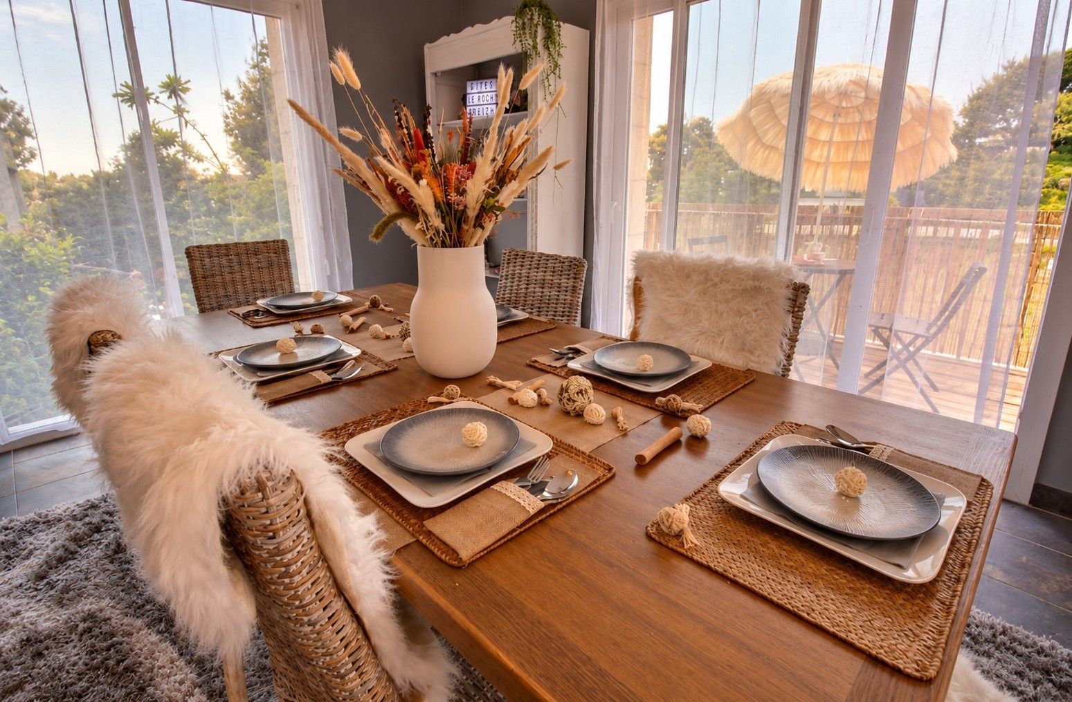 A dining table set for six with plates, cutlery, and a centerpiece.