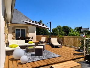 Un terrazza in legno con mobili da esterno, un portico coperto e un muro in pietra.