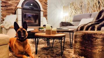 Una sala de estar acogedora con chimenea, un sofá, una mesa de centro y un perro.