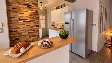 Une cuisine moderne avec un plan de travail en bois, un réfrigérateur en acier inoxydable et une plante en pot.