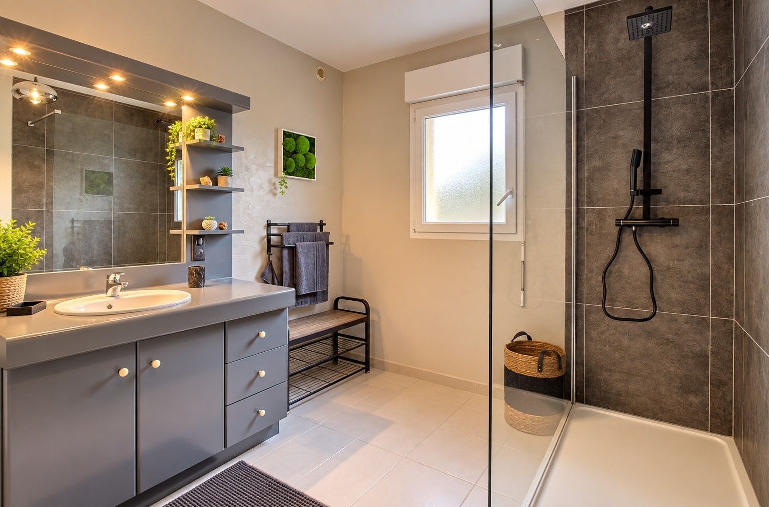 A modern bathroom with a large mirror, a sink, a shower, and a window.