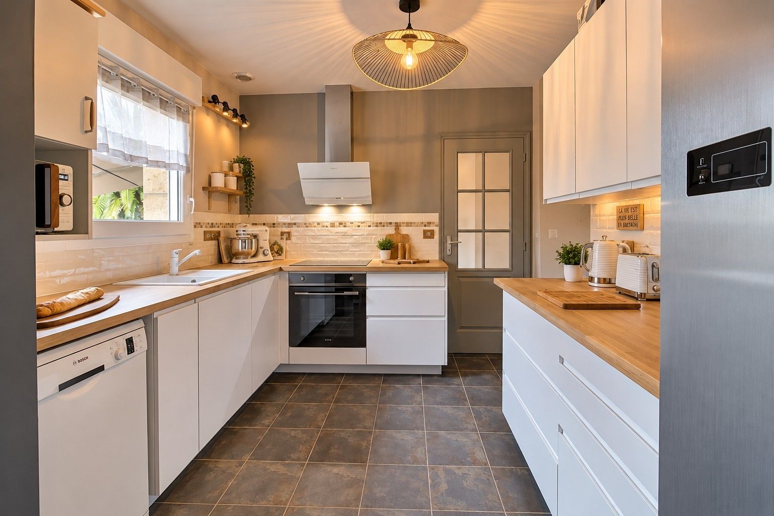 A modern kitchen with white cabinetry, a Bosch dishwasher, a built-in oven, and a wooden countertop.