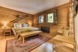 A wooden room with a bed, a bench, a chair, a window with curtains, and a radiator. - Ferme du Savoy · Wake up inside the Alps (Chamonix)