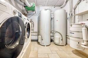 A laundry facility with industrial washing machines and large water tanks. - Ferme du Savoy · Wake up inside the Alps (Chamonix)