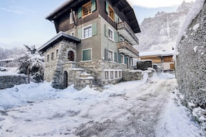 Ein mehrgeschossiges Gebäude mit Stein- und Holzwand, einem Steineingang und einer verschneiten Landschaft.