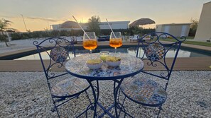 Ein Tisch am Pool mit zwei Gläsern Orangensaft, einer Schüssel Chips und einer Kerze.