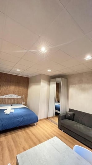 Quarto com cama, sofá, mesa e espelho.