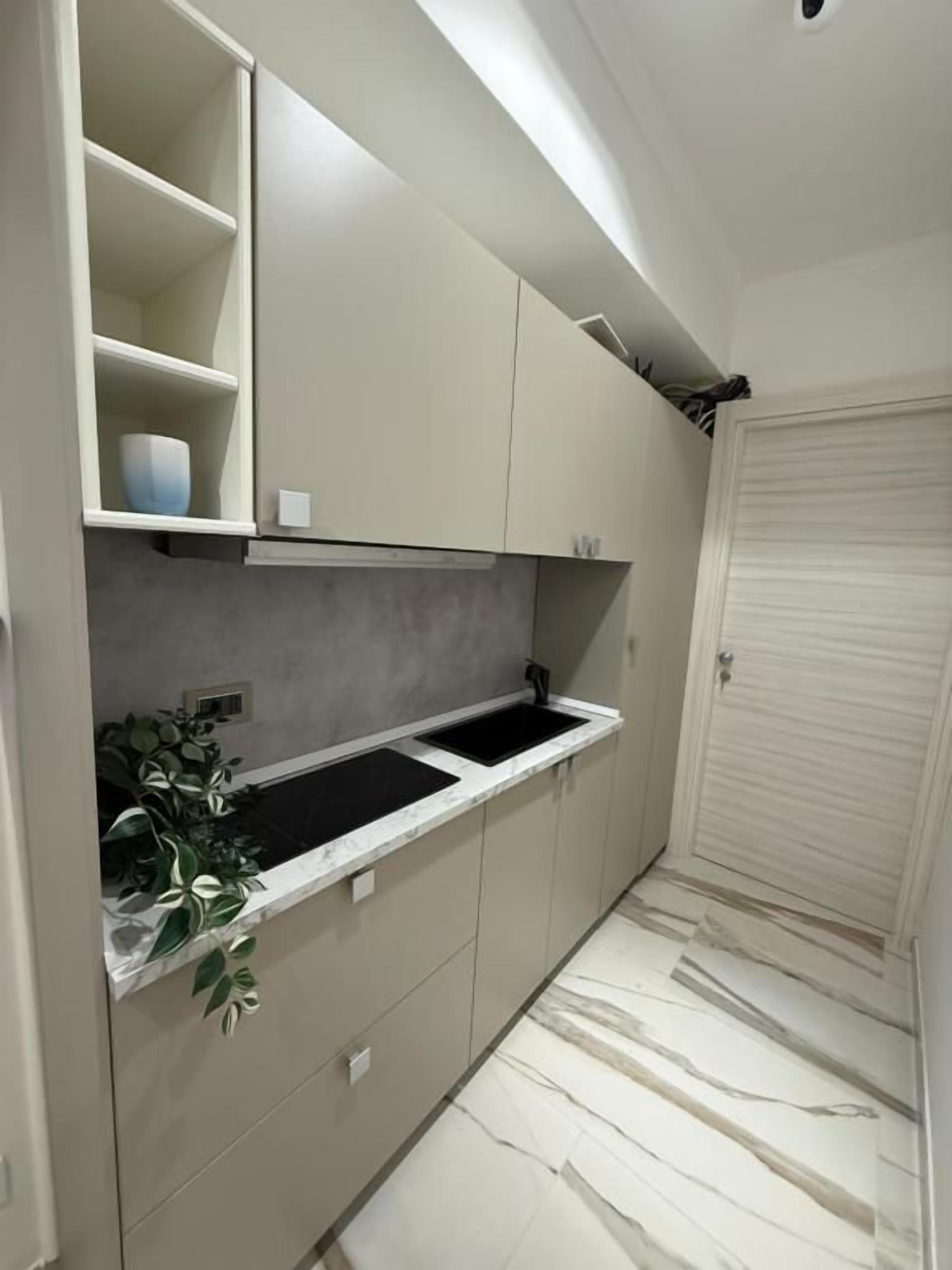A narrow kitchen with a countertop, cabinets, and a sink.