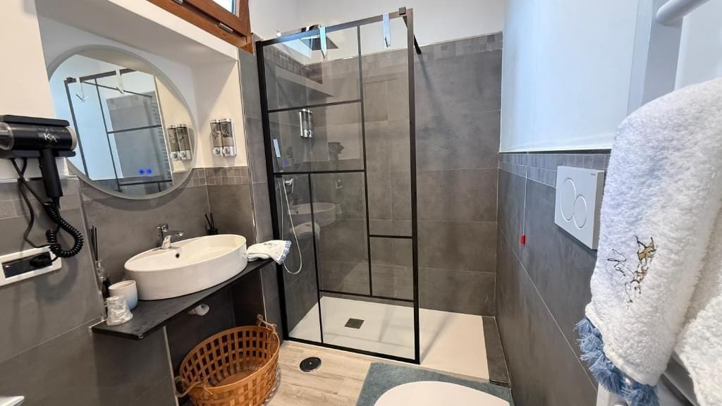 Ein modernes Badezimmer mit Duschkabine aus Glas, Waschbecken und Handtuchhalter.