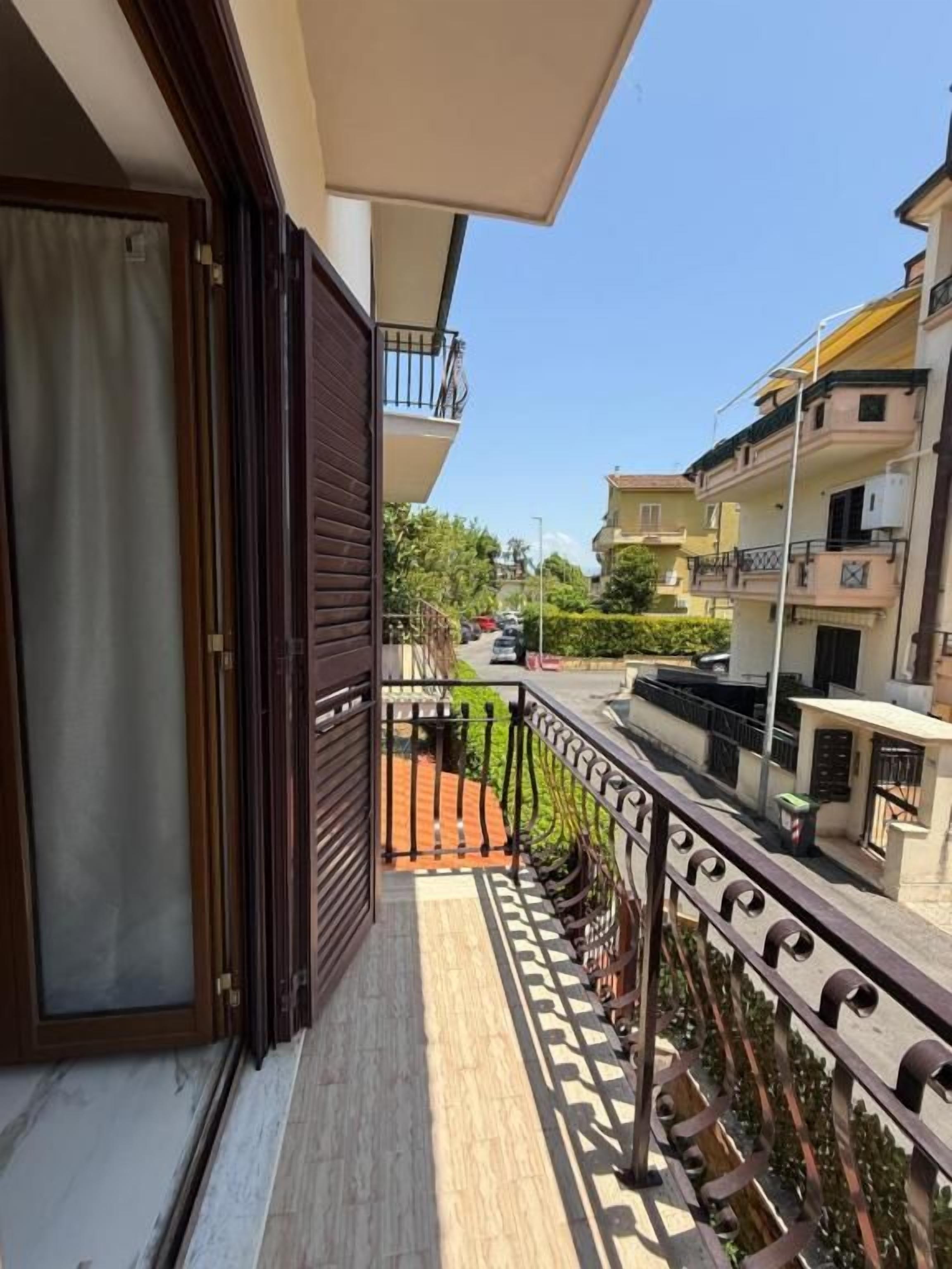 Ein Balkon mit Blick auf eine Straße, einer geschlossenen Tür und einem Geländer.