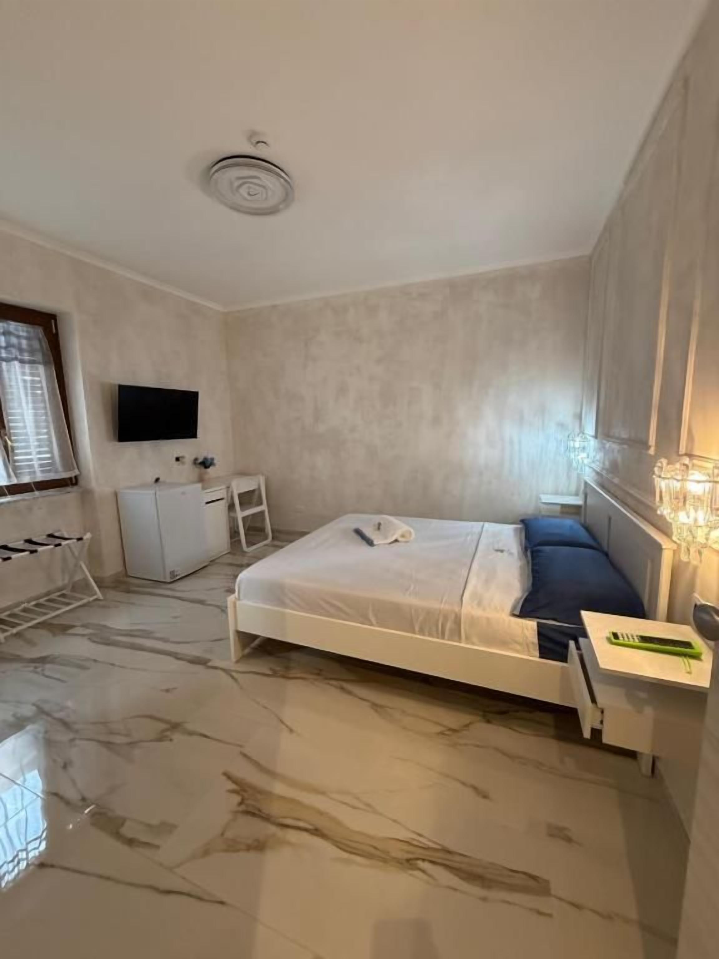 Un dormitorio con cama, mesita de noche y televisor montado en la pared.