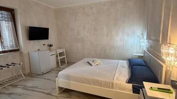 Un dormitorio con cama, mesita de noche y televisor montado en la pared.