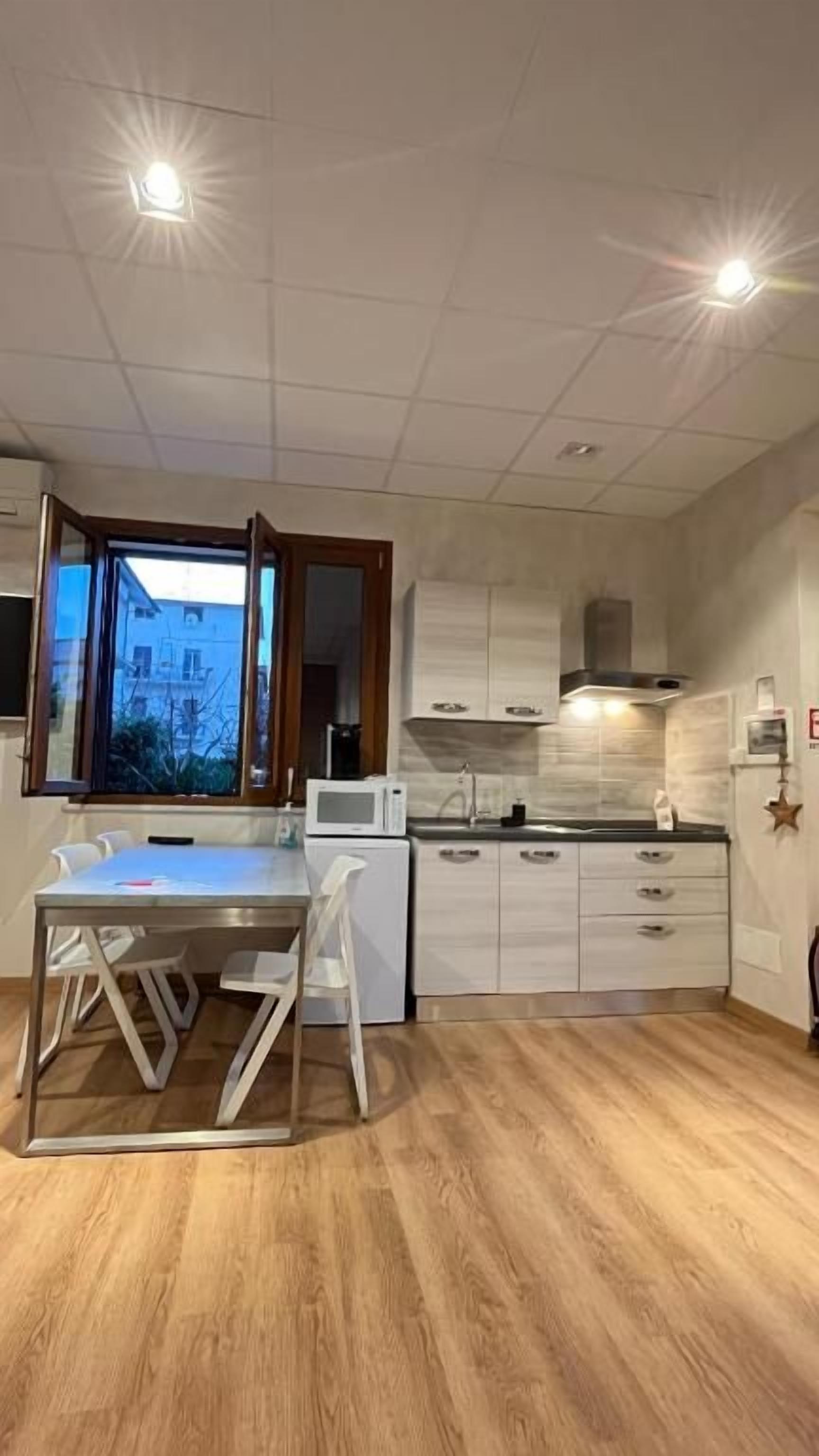 Een moderne keuken met een centraal eiland, witte kasten en een raam met open deur.