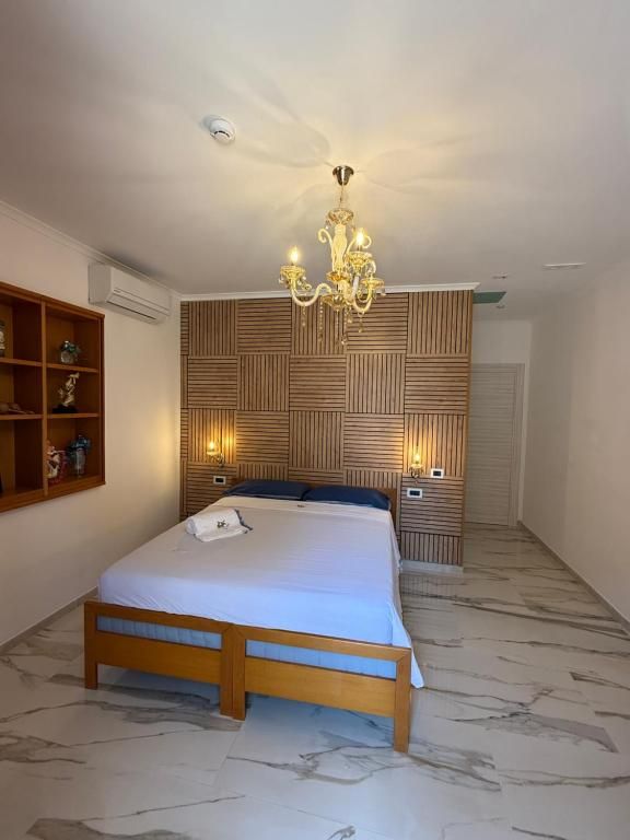 Een slaapkamer met een bed, een kroonluchter, een wandplank en een vloer met een patroon.