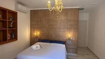 Een slaapkamer met een bed, een kroonluchter, een wandplank en een vloer met een patroon.