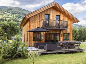 A wooden cabin with a balcony, outdoor seating, and a hot tub. - One-bedroom Cabin (Sankt Georgen am Kreischberg)