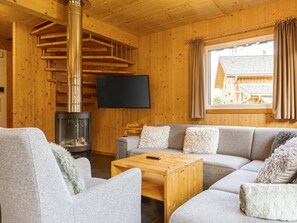 A cozy cabin interior with a fireplace, a sofa set, and a television. - One-bedroom Cabin (Sankt Georgen am Kreischberg)