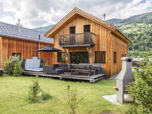 A wooden cabin with a balcony, outdoor seating, and a barbecue area. - One-bedroom Cabin (Sankt Georgen am Kreischberg)