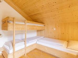 A wooden bunk bed room with a ladder, a small bedside table, and a wall-mounted light fixture. - One-bedroom Cabin (Sankt Georgen am Kreischberg)