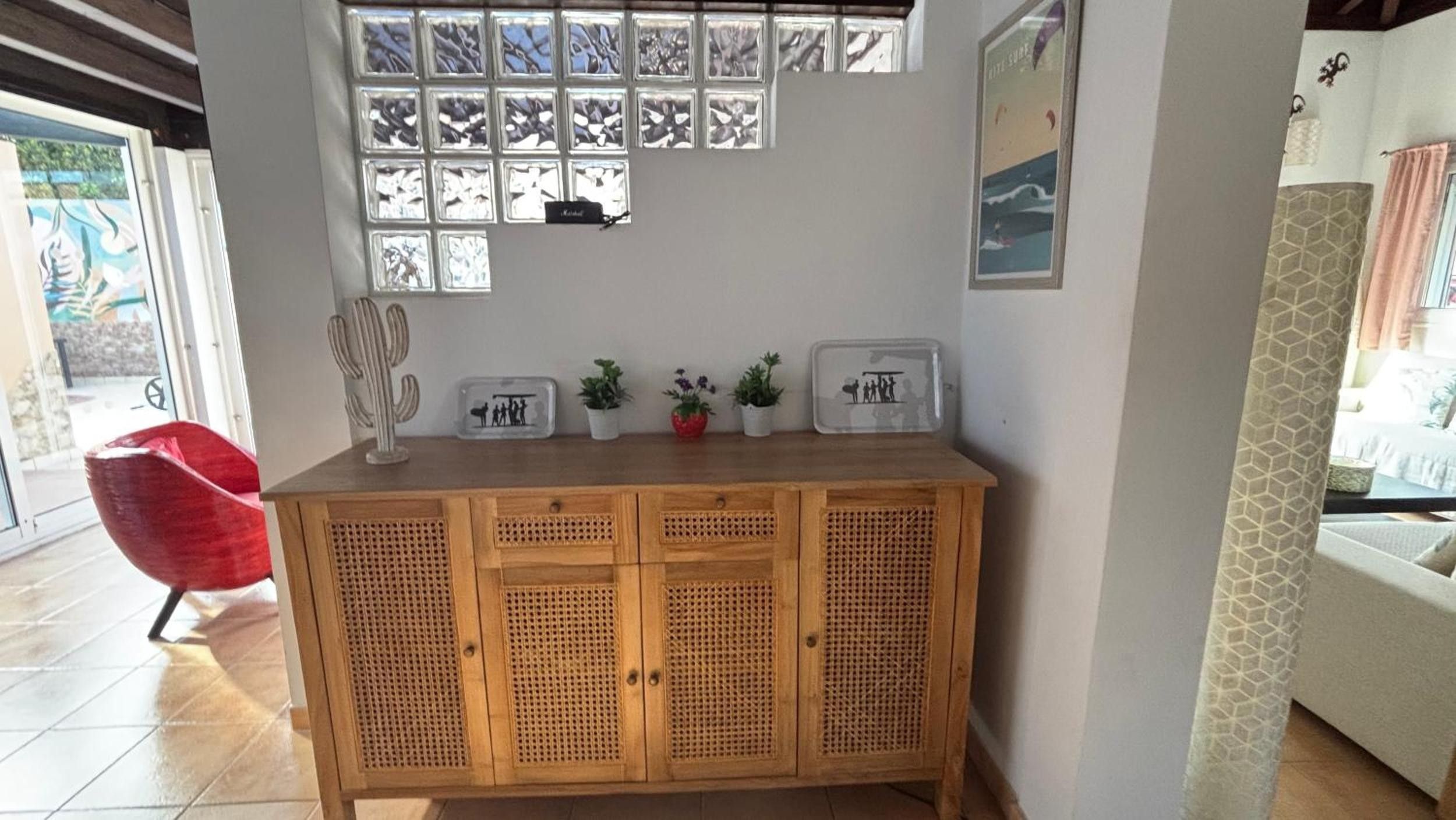 Un mueble de madera con paneles decorativos, una escultura de cactus y cuadros en una pared.