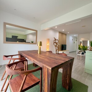 Uma sala de jantar com mesa de madeira, cadeiras, abajur e espelho na parede.