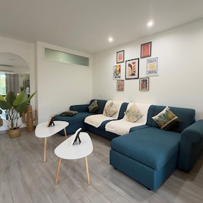 Un soggiorno moderno con un divano componibile, due tavolini bianchi e cuscini decorativi.