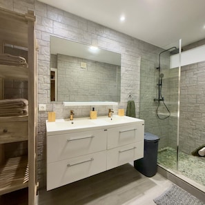 Un bagno con un mobile lavabo bianco, uno specchio grande e un box doccia in vetro.