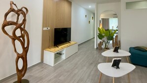 Ein modernes Wohnzimmer mit Flachbildfernseher, Holzpaneelwand und einer einzigartigen abstrakten Skulptur.
