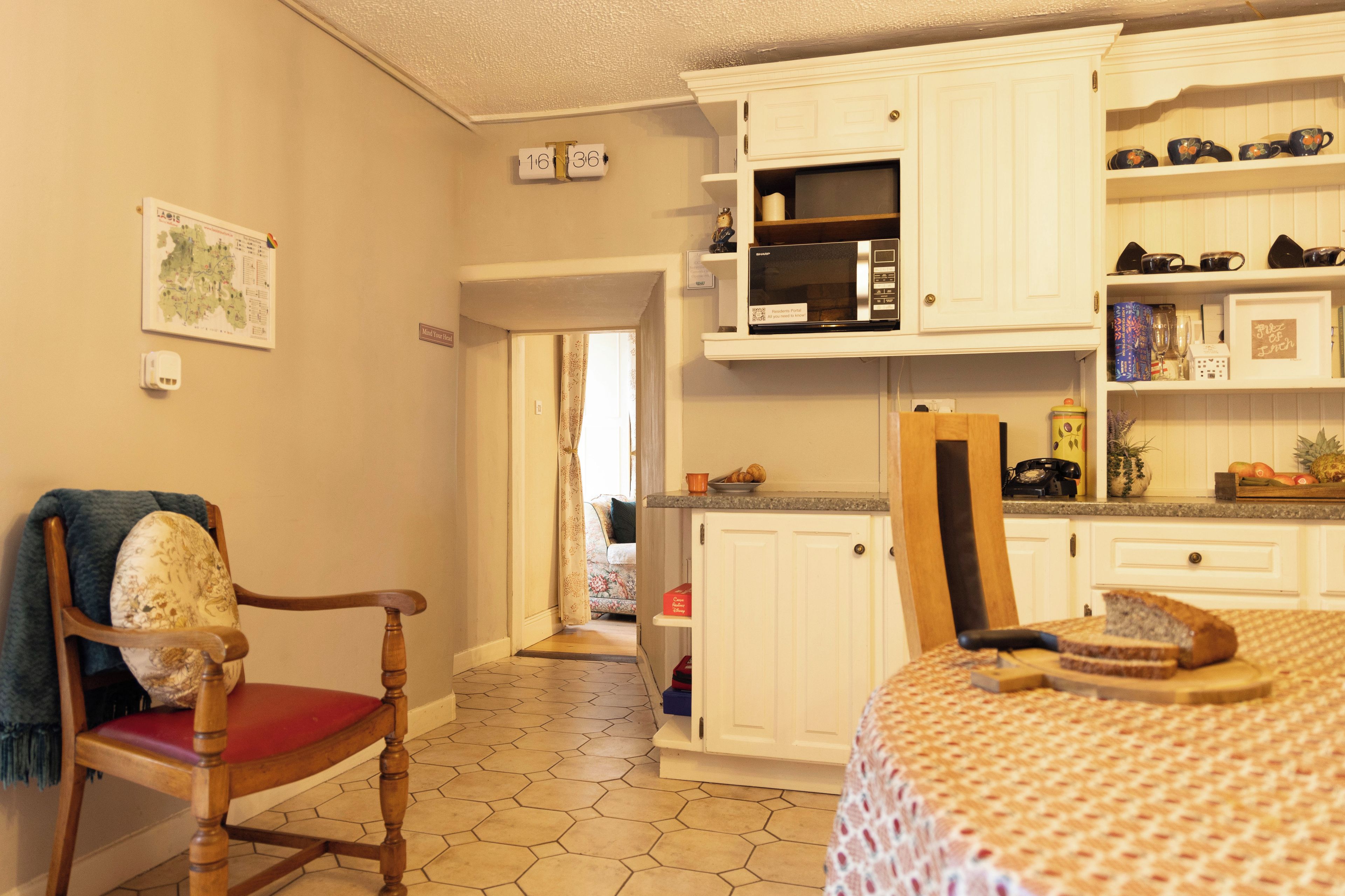 A kitchen with white cabinets, a microwave, and a dining area with a table and chairs.