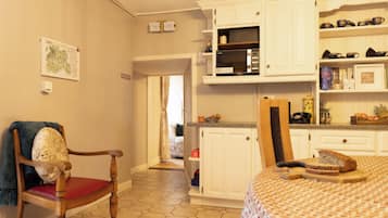 A kitchen with white cabinets, a microwave, and a dining area with a table and chairs.