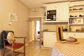 A kitchen with white cabinets, a microwave, and a dining area with a table and chairs.