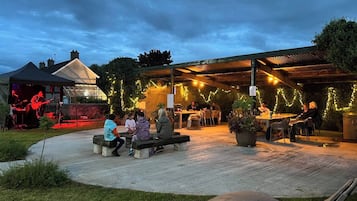 An outdoor patio area with seating arrangements and a stage for live music.