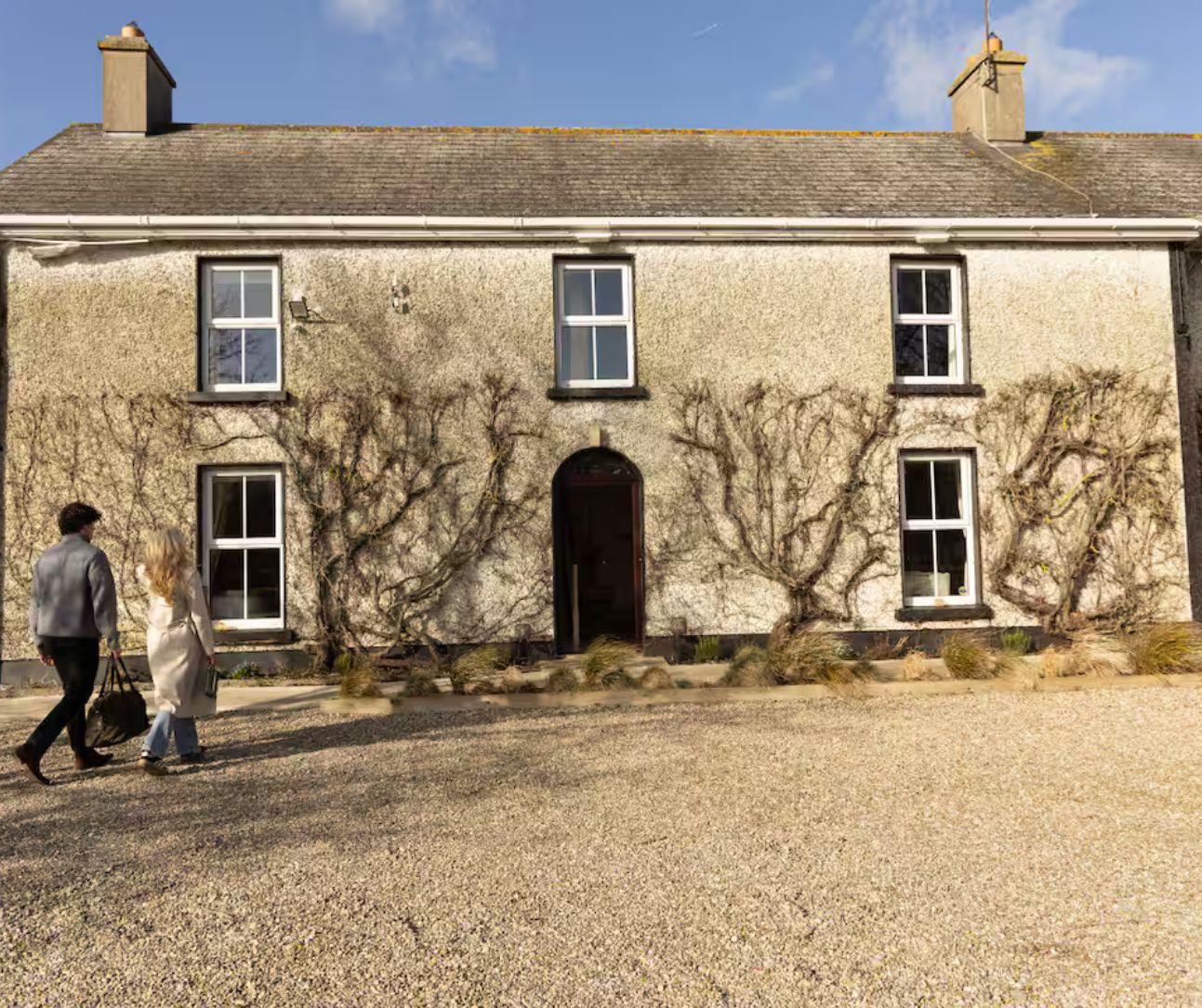 A two-story building with a gravel driveway and a large arched entrance.