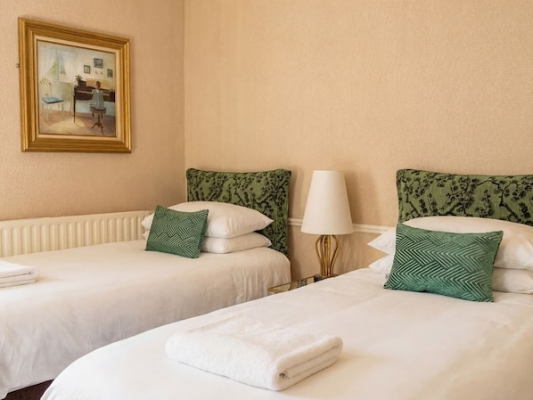 Une chambre d’hôtel avec deux lits, un radiateur, une lampe et un tableau encadré au mur.
