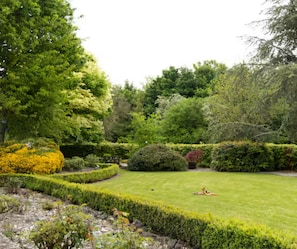 A well-maintained garden with manicured lawns, hedges, and a variety of trees.