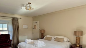 A hotel room with a large bed, a red chair, a bedside table with a lamp, and a chandelier. - Fitz Of Inch - Guest House Rooms (Stradbally)