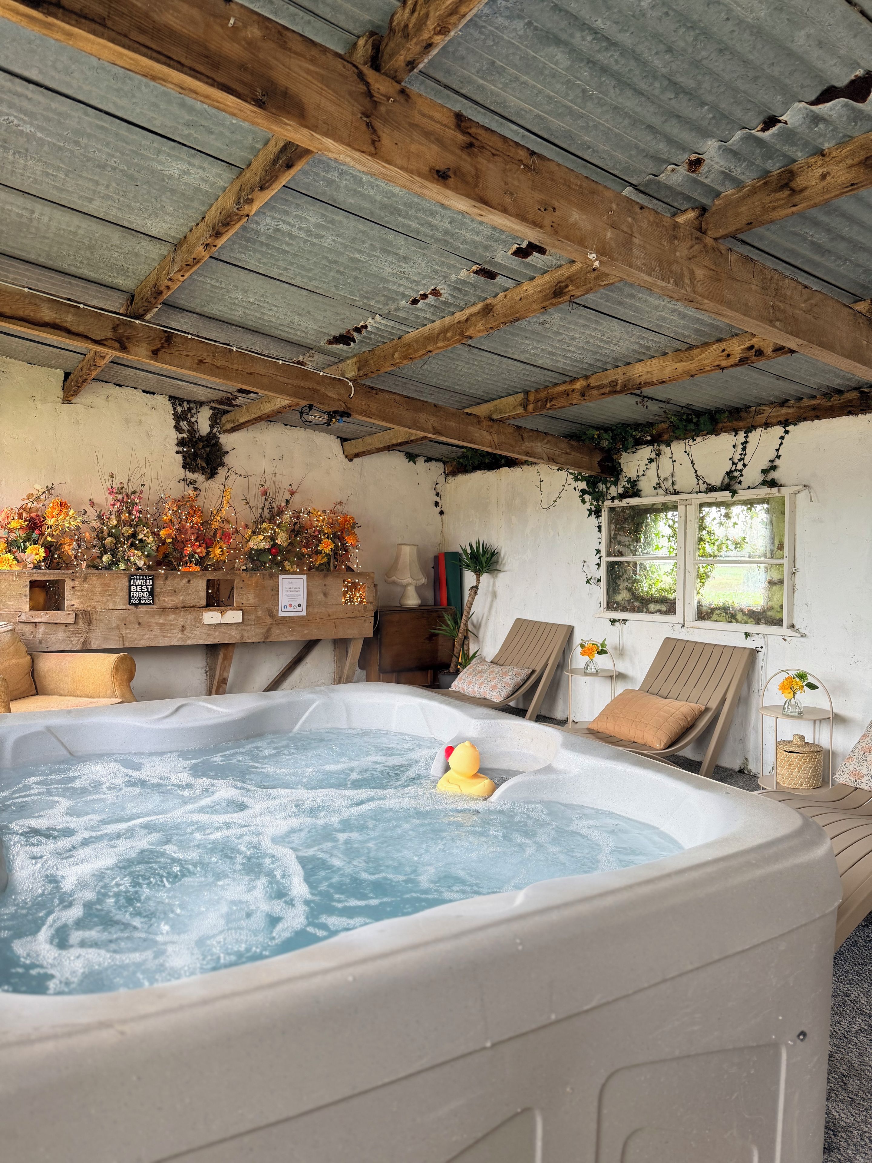 Un jacuzzi con un patito de goma, vigas de madera y un interior rústico.