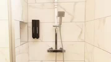 A shower area with a handheld showerhead and a wall-mounted control panel.