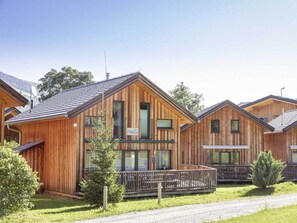 A row of wooden cabins with a central building featuring large windows and a sign. - One-bedroom Cabin (Sankt Georgen am Kreischberg)