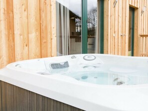 A hot tub with a wooden exterior wall and a glass door leading to an outdoor area. - One-bedroom Cabin (Sankt Georgen am Kreischberg)