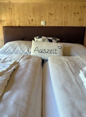 A bed with white bedding and a pillow with the word 'Auszeit' and a heart symbol. - One-bedroom Cabin (Sankt Georgen am Kreischberg)