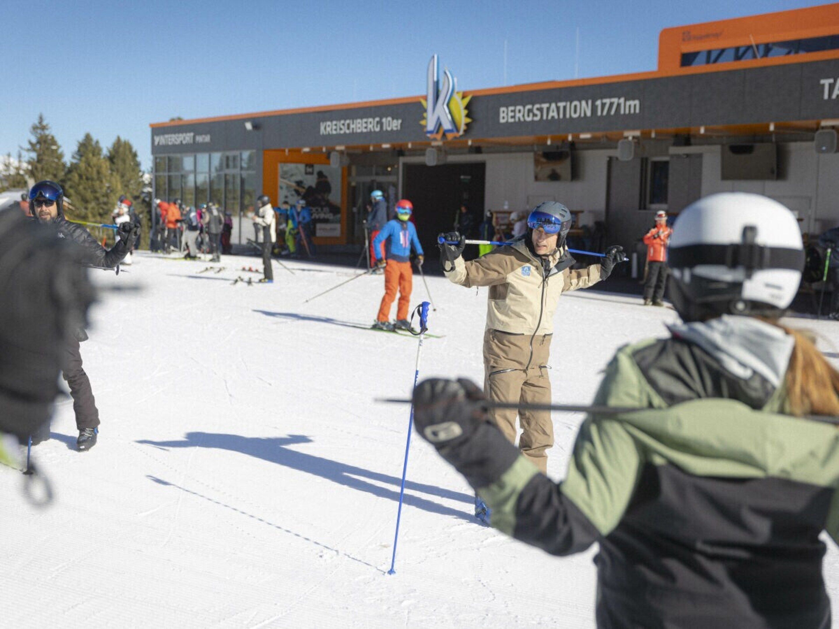 A ski slope with skiers and a building labeled 'BERGSTATION 1771m' in the background.