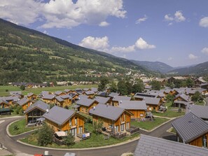 A cluster of wooden cabins with sloped roofs, surrounded by green hills and a clear sky. - One-bedroom Cabin (Sankt Georgen am Kreischberg)