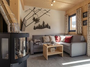 A cozy living room with a fireplace, a sofa, and a coffee table. - One-bedroom Cabin (Sankt Georgen am Kreischberg)