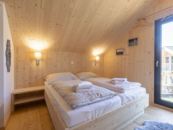 A wooden room with a bed, two wall-mounted lights, and a window. - One-bedroom Cabin (Sankt Georgen am Kreischberg)